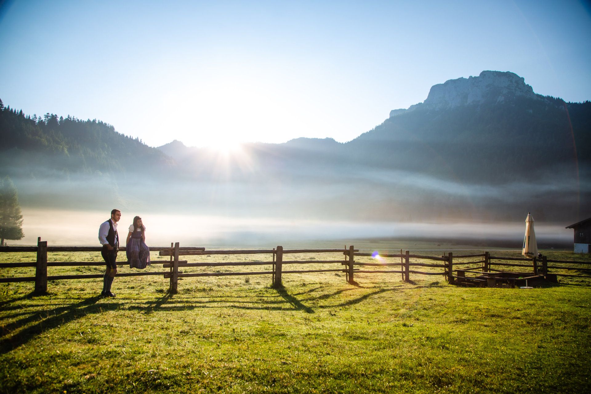 Vater und Tochter sitzen auf einem Zaun in den bergen