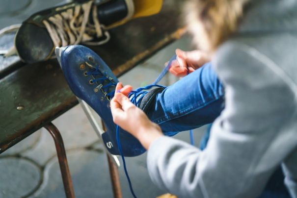 Frau zieht sich Schittschuhe an.