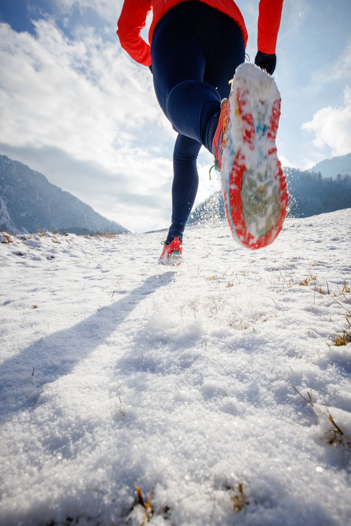 Fokus auf die Laufschuhsohlen beim Winterjoggen.