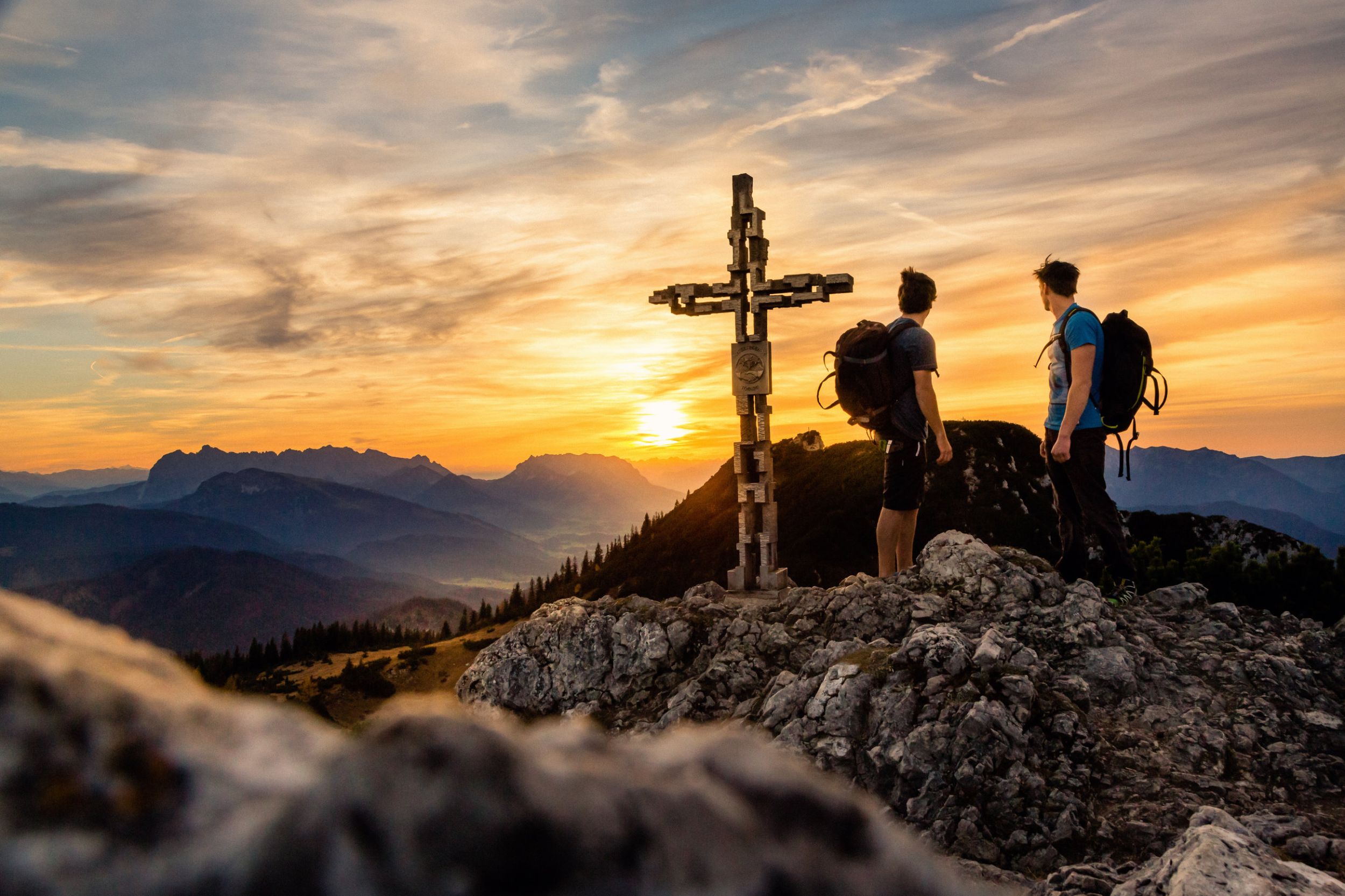 Zwei Kletterer am Gipfelkreuz der Hoerndlwand