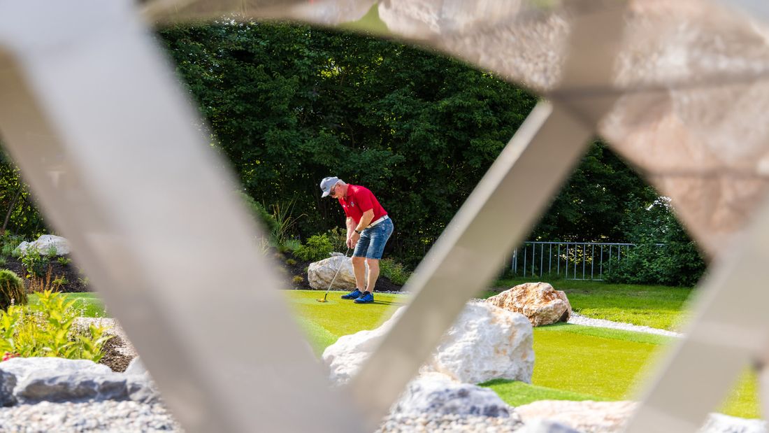 Gast steht am Adventure Golf Abschlagsort.