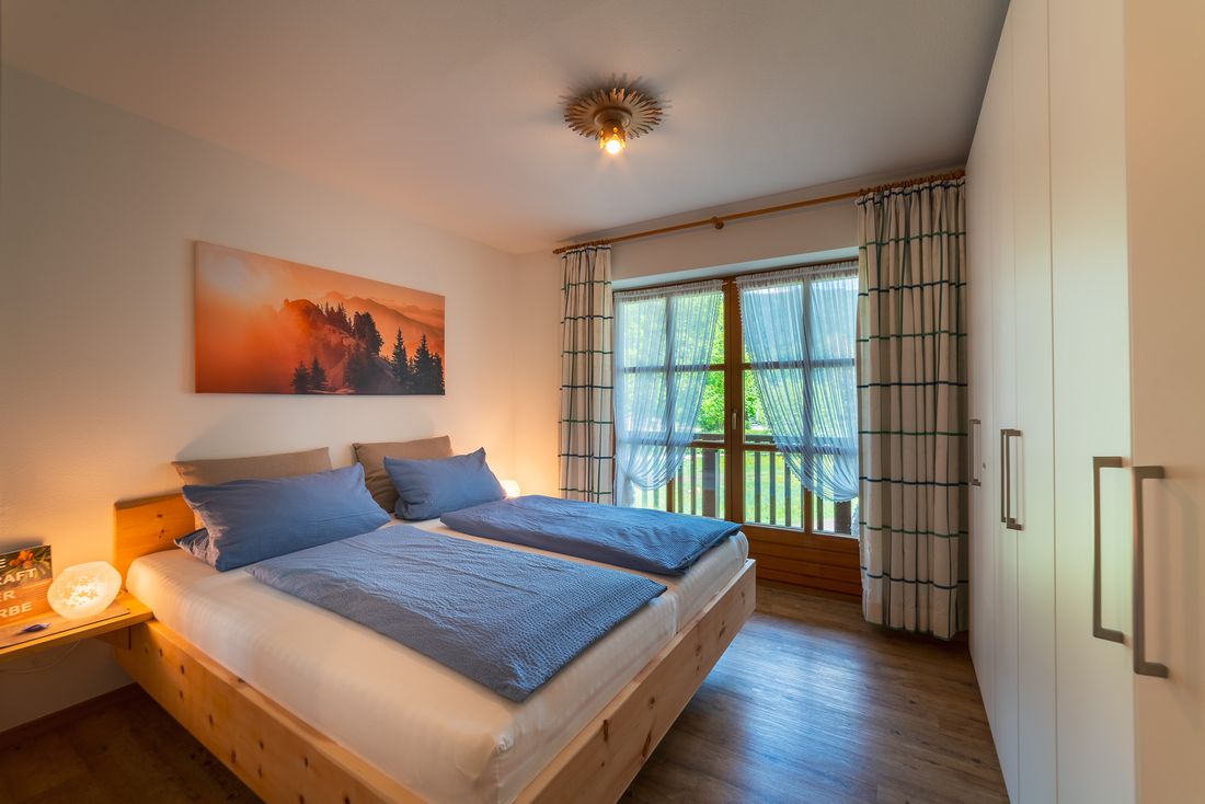 Schlafzimmer mit Zirbenbett und Balkon