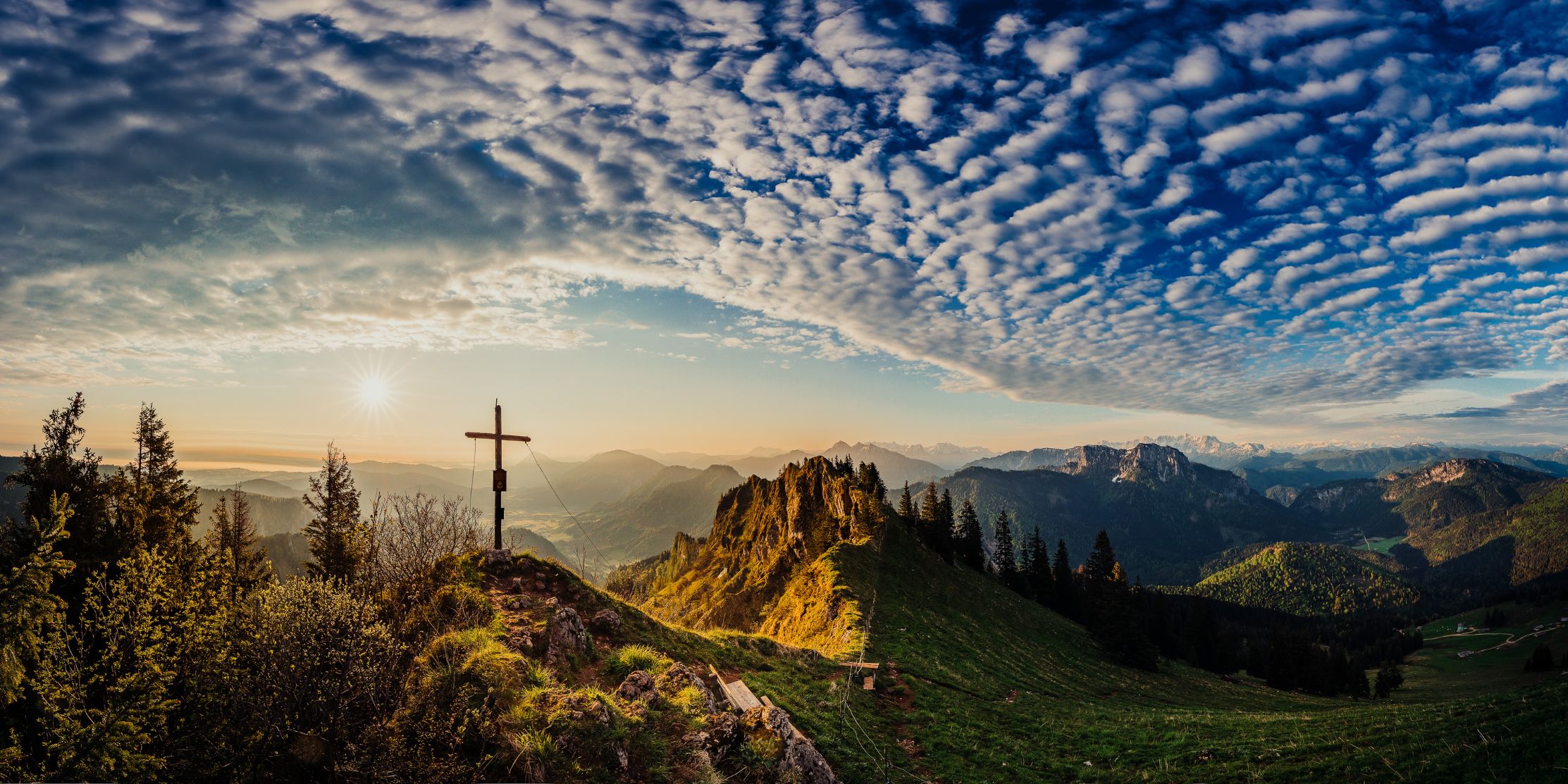Blick über die Chiemgauer Berge und einem Gipfelkreuz